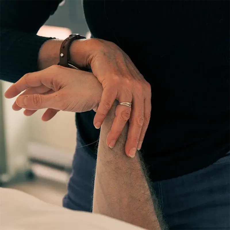 Caroline Rochez kinésiologue à Uccle effectue un test musculaire du bras sur un patient.